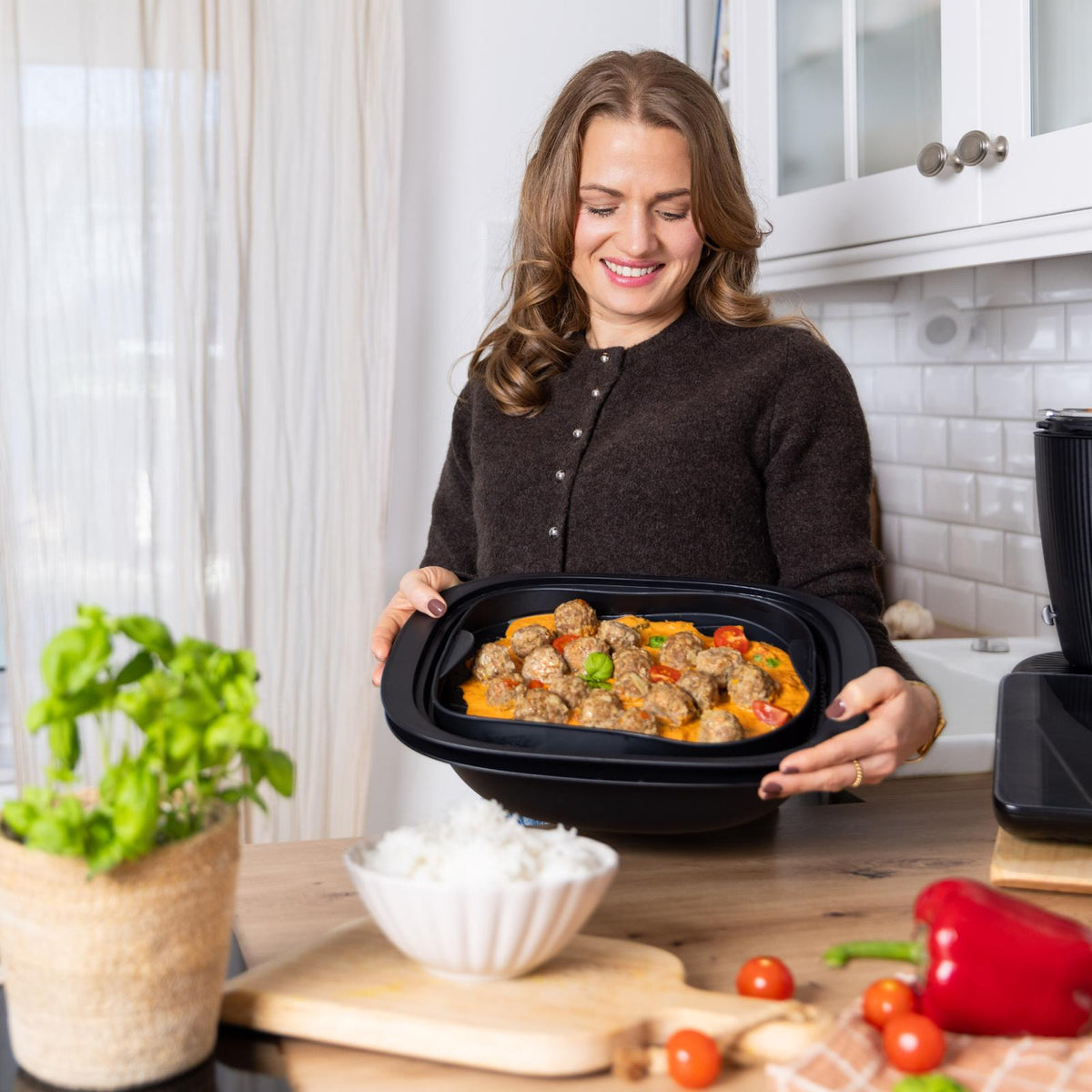 Sandra Wall von fitgemixt hält ihren cleveren FitEinleger für TM7®* passend für den Thermomix®* und mit selbstgemachten Hackbällchen in Tomatensoße in Händen
