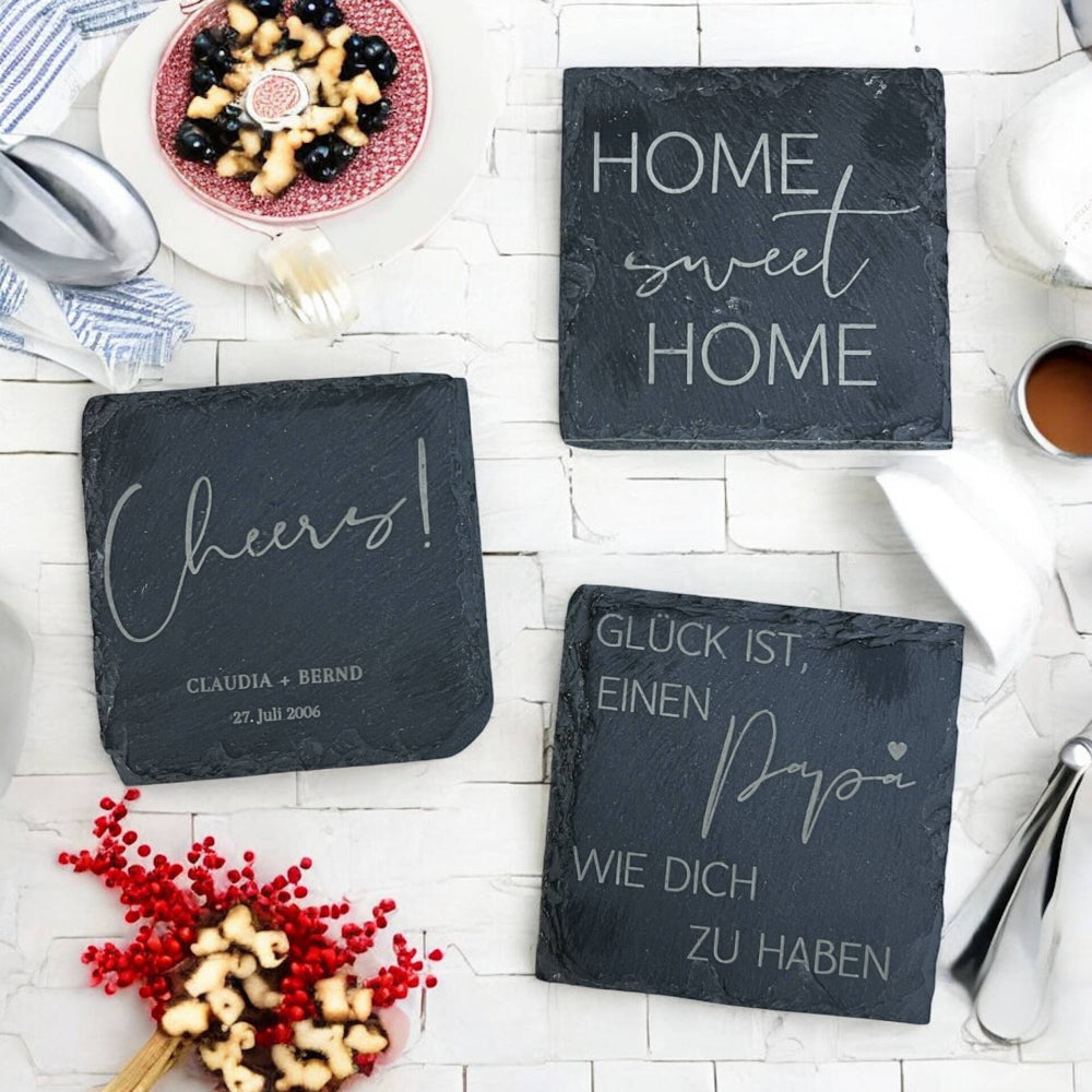 Personalisierte Schiefer-Untersetzer mit liebevollen Sprüchen wie 'Home Sweet Home' und 'Cheers!' – für gemütliche Momente im fitgemixt Onlineshop erhältlich.